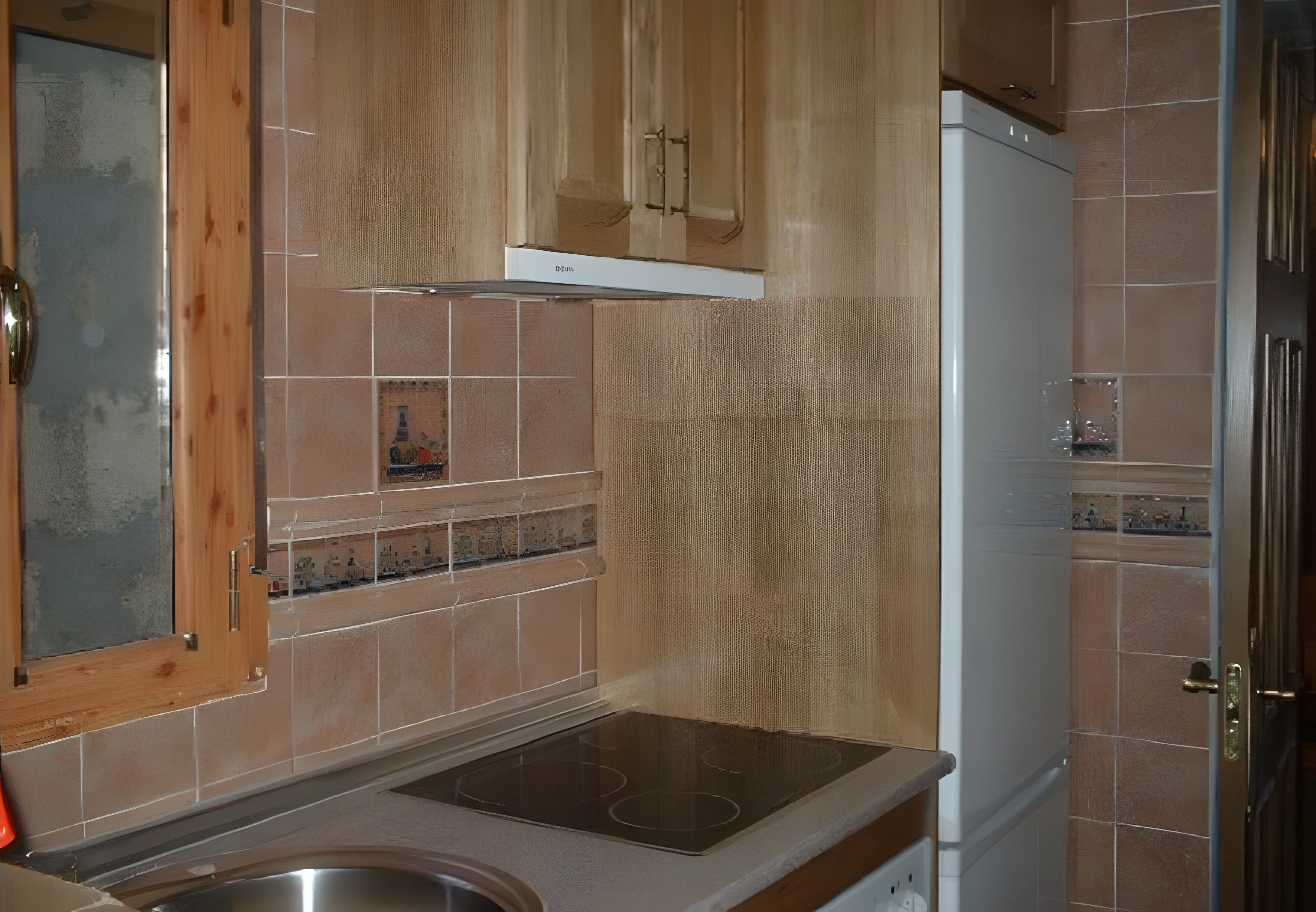 Una cocina con armarios de madera, un lavamanos de acero inoxidable y un refrigerador blanco.