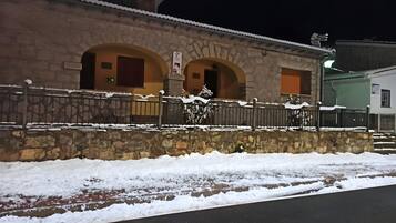 Edificio de piedra con arcos y una valla de metal, rodeado de nieve.