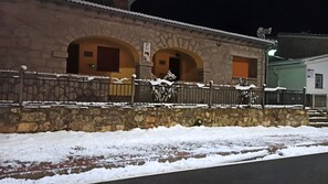 Edifício de pedra com arcadas e cerca de metal, rodeado por neve.