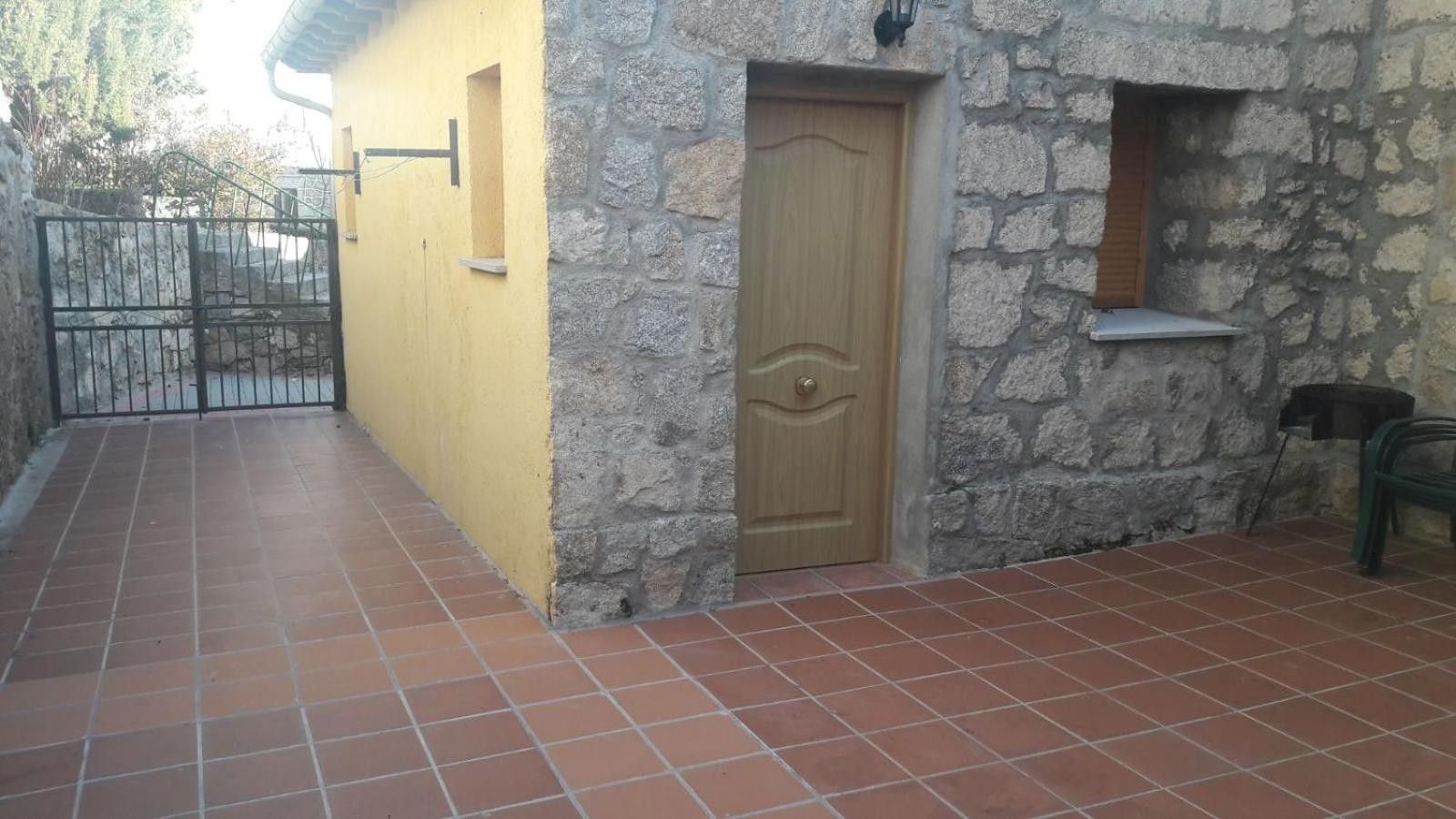 Un edificio con pared de piedra, puerta de madera y suelo de baldosas.