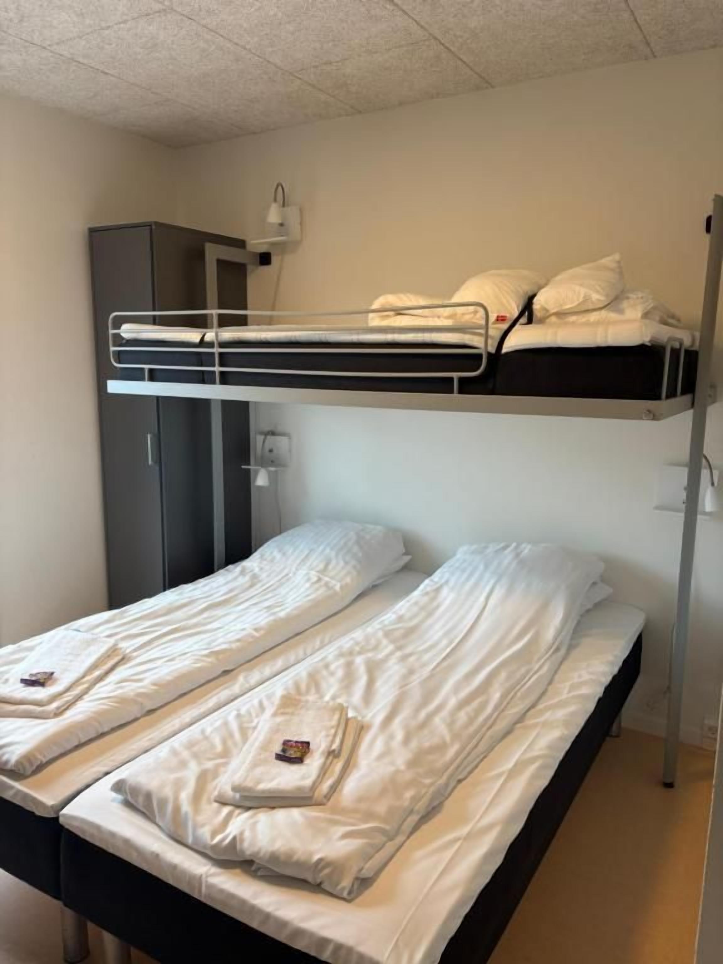 A bunk bed with two beds, a wardrobe, and a bedside lamp.