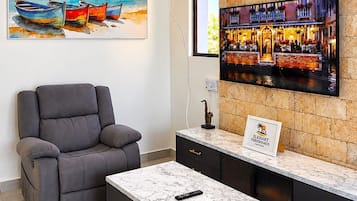 A modern hotel lobby with a bar area, a reclining chair, and a marble coffee table.
