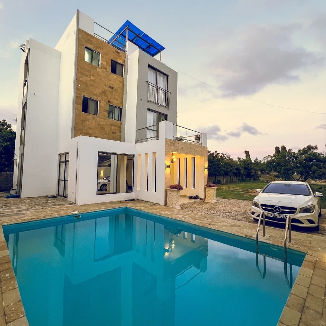 Une maison moderne à deux étages, avec une piscine en premier plan.
