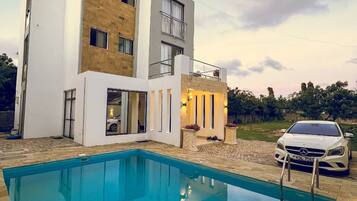 Une maison moderne à deux étages, avec une piscine en premier plan.