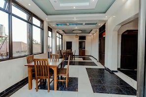 A hotel lobby with a dining area, large windows, and a modern ceiling design. - Hulcity Gold Hotel (Kampala)