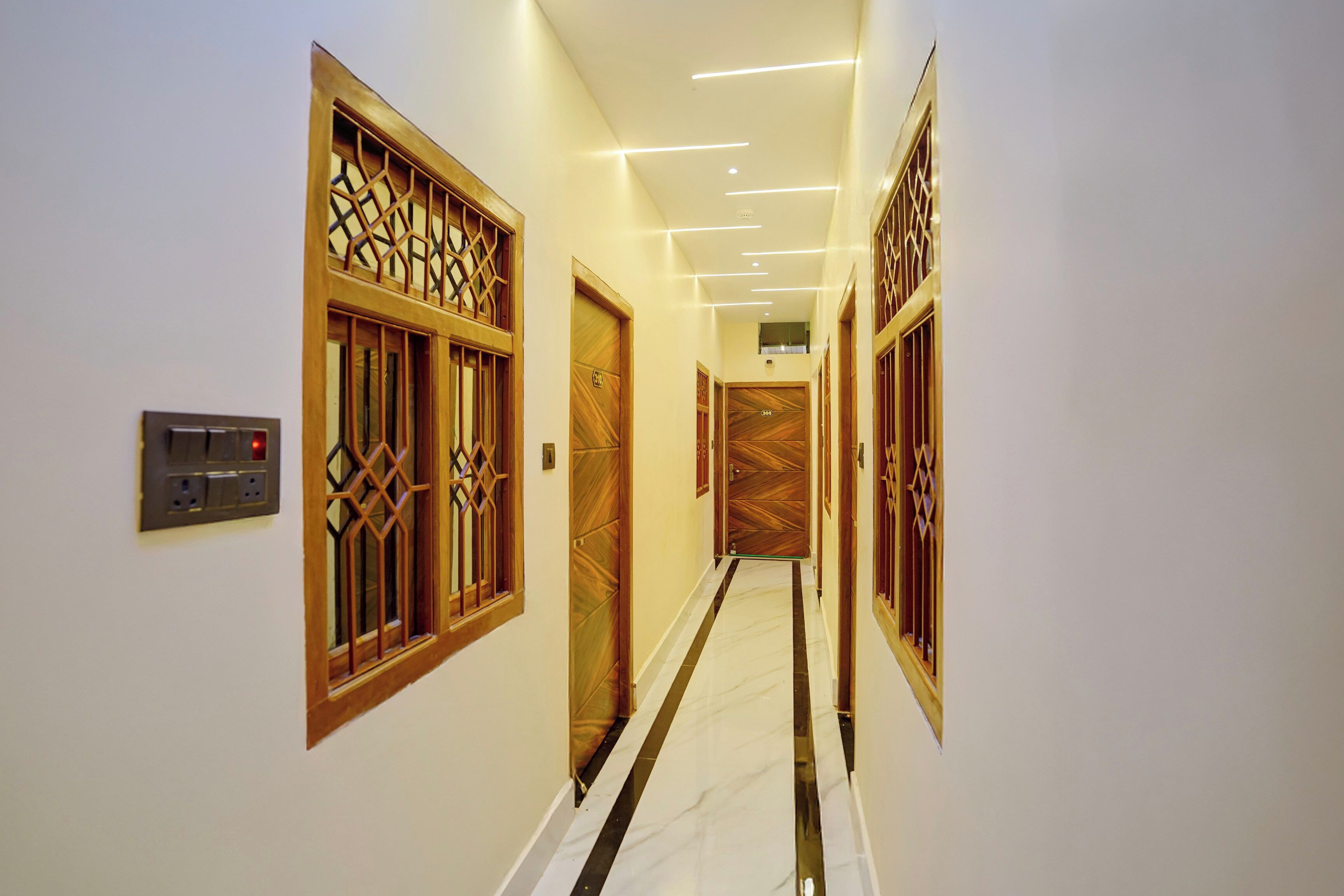 A hallway with wooden doors and a modern light fixture.