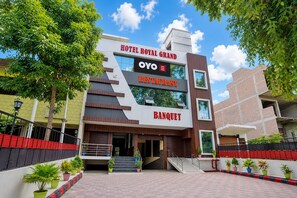 Un hotel moderno con un cartel llamativo del Royal Grand Hotel, un restaurante y un salón de banquetes.