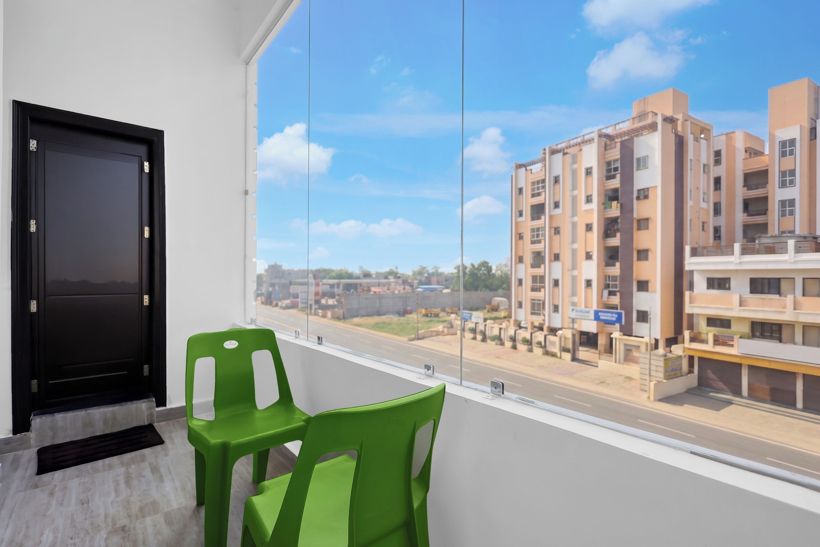 A room with a large window, a black door, and two green chairs.