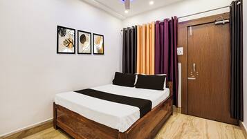 Un dormitorio con cama de madera, ventilador de techo y puerta con cortinas.