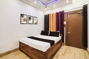 A bedroom with a wooden bed, a ceiling fan, and a door with curtains. - Hotel O JS Palace (Gorakhpur)