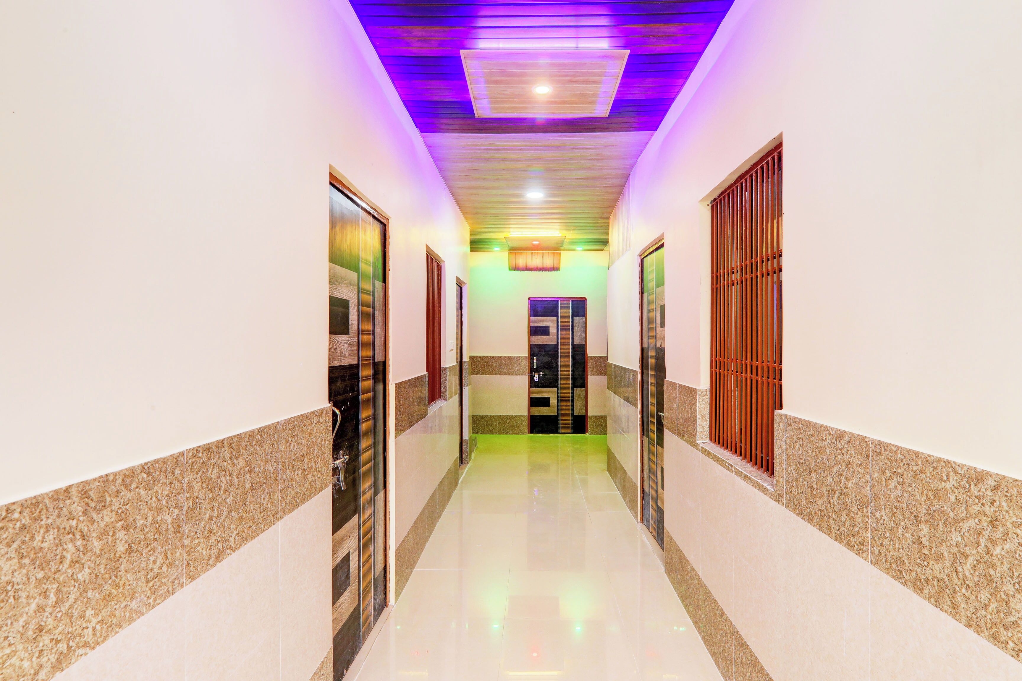 A corridor with a polished floor, a ceiling with a recessed light, and a door with a metal gate.