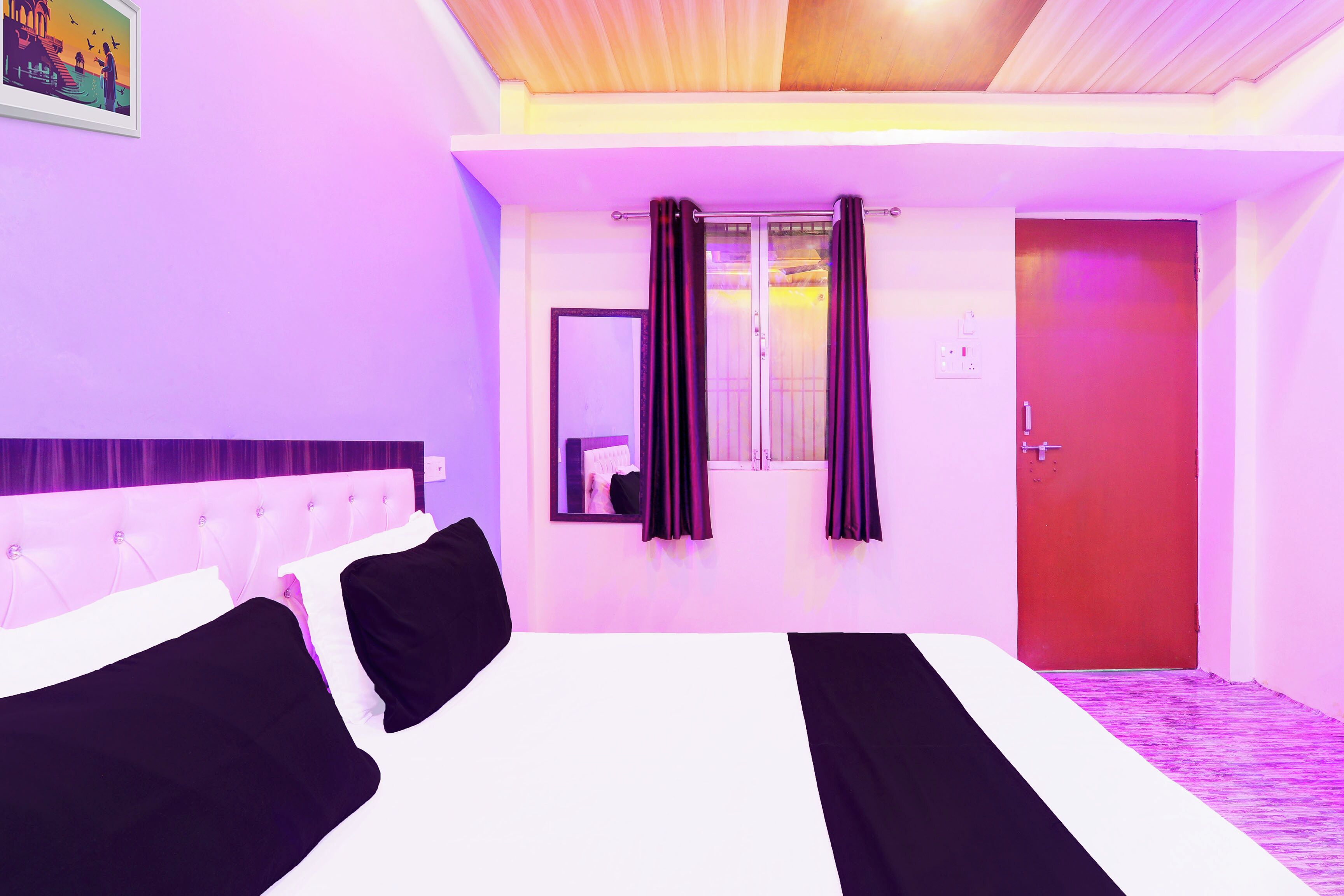 A hotel room with a bed, a mirror, curtains, and a door.