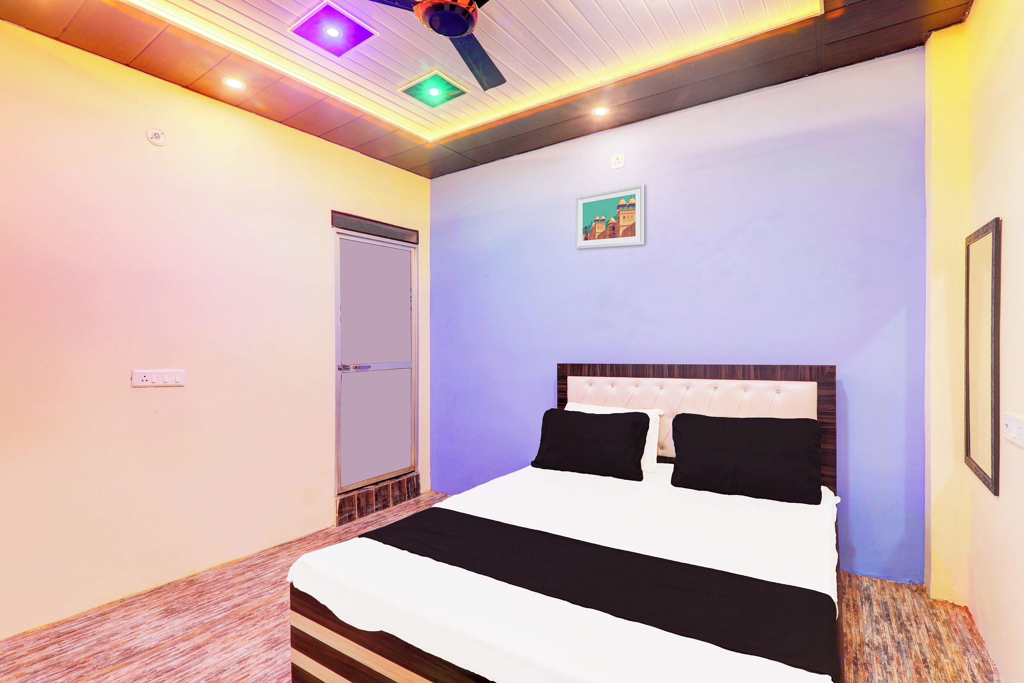 A bedroom with a bed, a ceiling light fixture, and a wall-mounted picture.