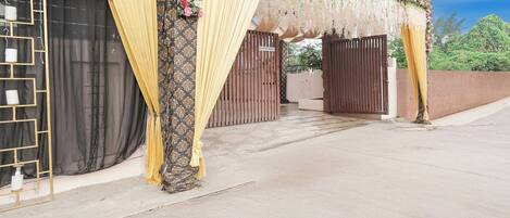 Una entrada protegida por una reja con cortinas decorativas y arreglos florales.