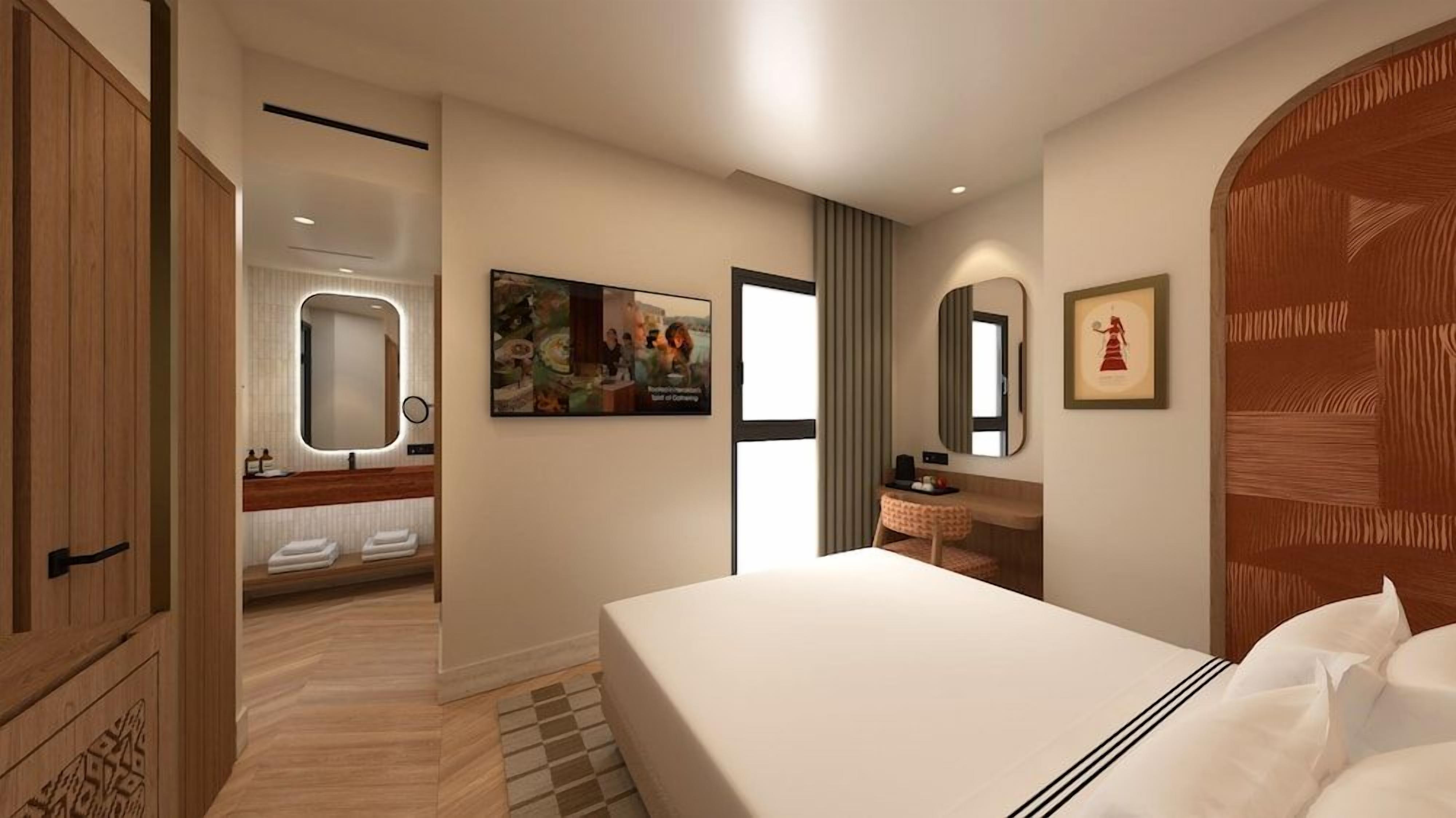 Een moderne hotelkamer met een groot bed, een kaptafel met spiegel, en een deur naar de badkamer.
