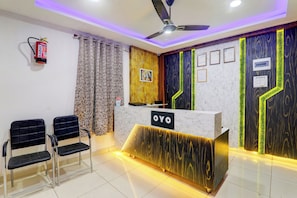 A reception area with a marble counter, two black chairs, a ceiling fan, and a fire extinguisher. - Hotel O Aayaansh (Gorakhpur)
