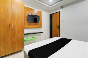 A bedroom with a bed, wooden wardrobe, a mirror, and a small kitchenette area. - Hotel O Aayaansh (Maharajganj)