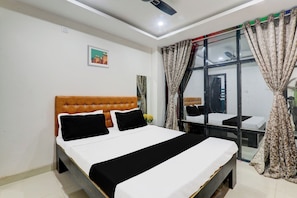 A hotel room with a bed, a window with curtains, a small table, and a wall-mounted picture. - Hotel O Aayaansh (Gorakhpur)