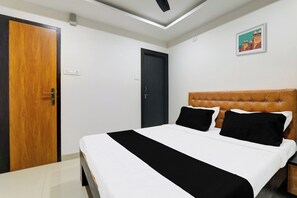 A hotel room with a bed, a wooden door, a dark-colored wardrobe, a ceiling light, and a framed picture on the wall. - Hotel O Aayaansh (Gorakhpur)