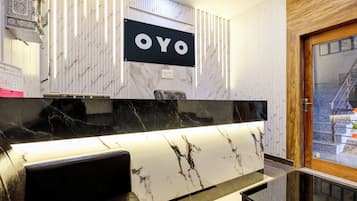 A modern kitchen with a marble countertop, a black and white sign above it, and a wooden door to the right.