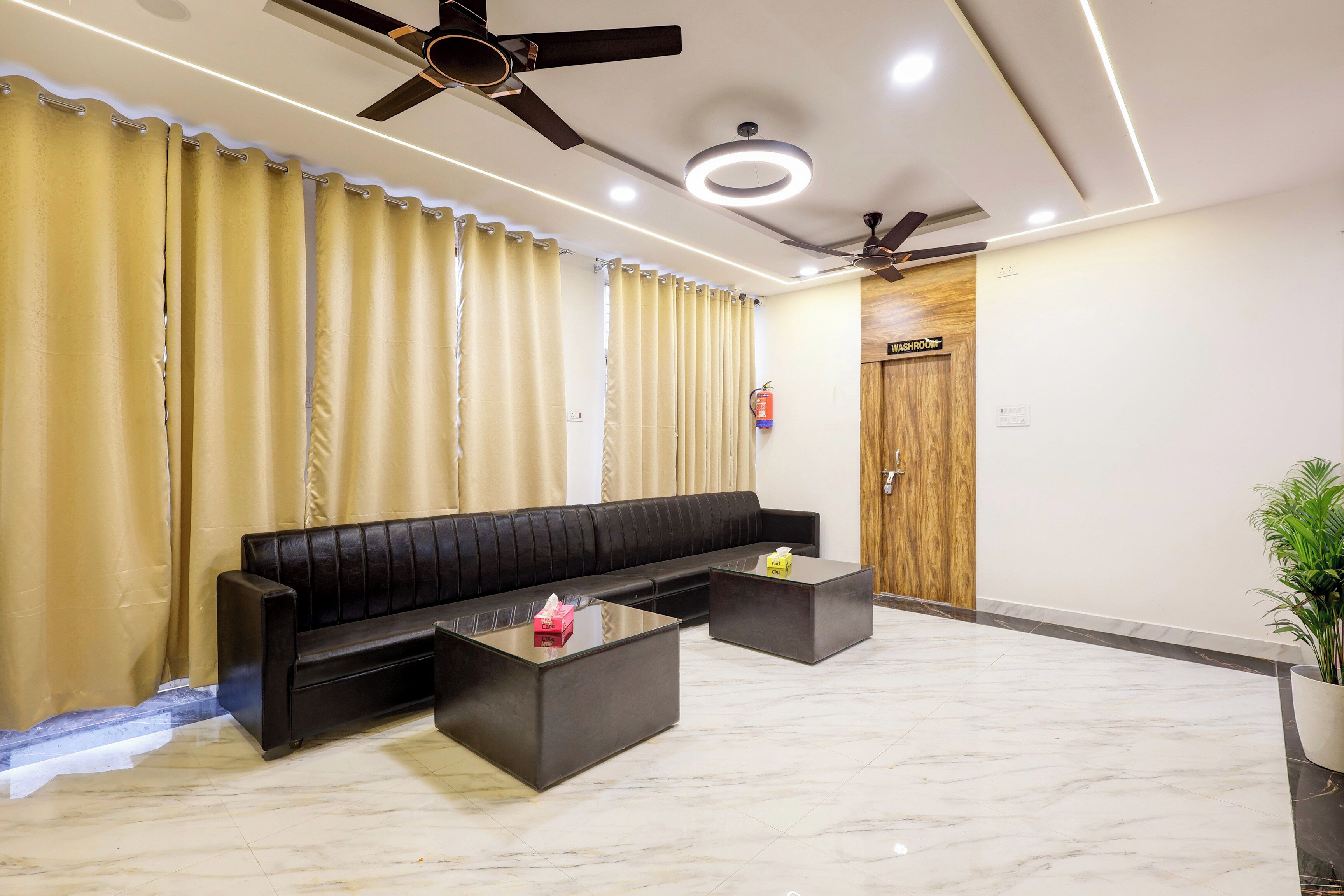 A modern living area with a black sofa, a glass coffee table, and a ceiling fan.