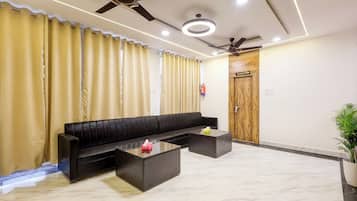 A modern living area with a black sofa, a glass coffee table, and a ceiling fan.