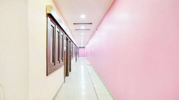 A corridor with doors on one side and a pink wall on the other.