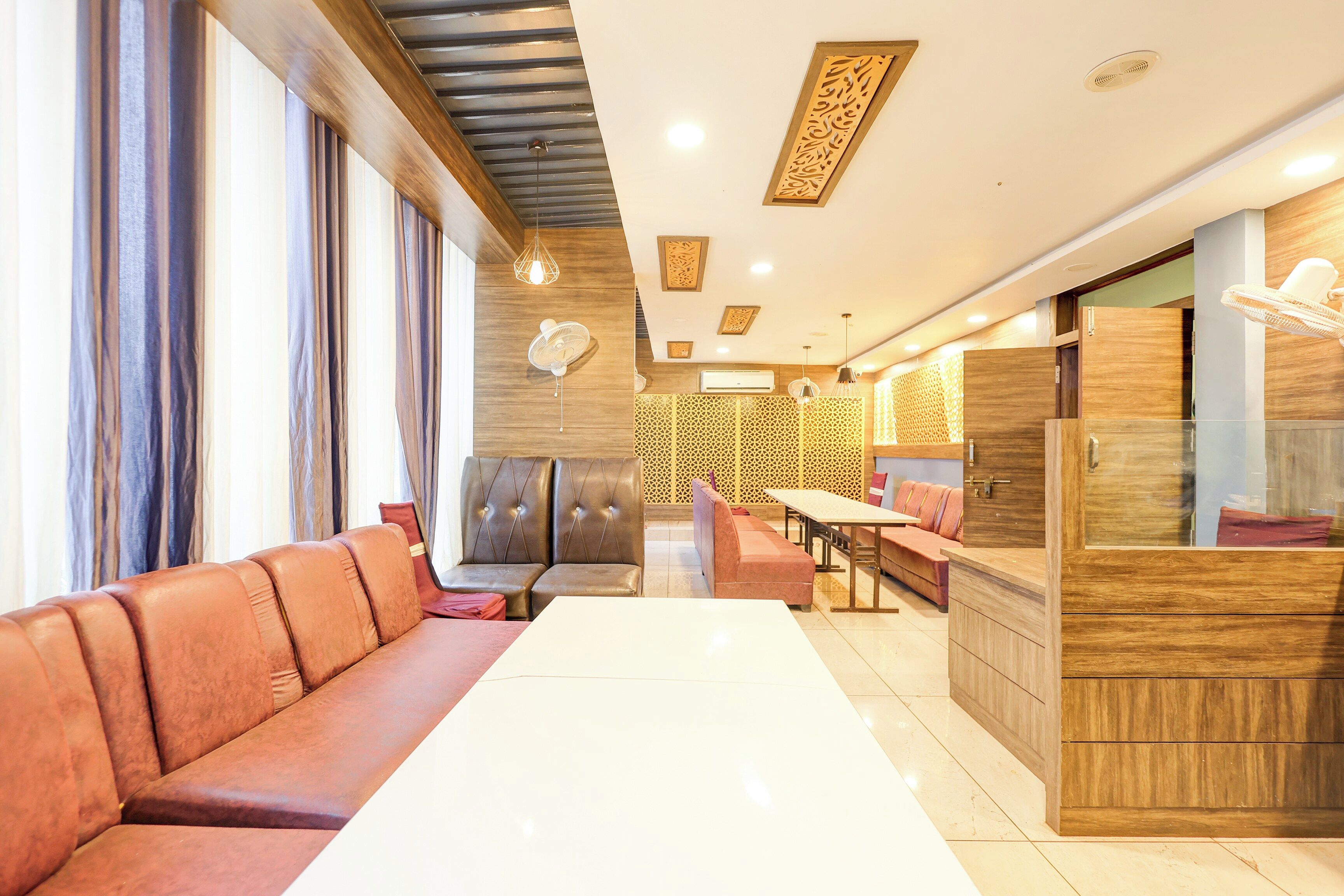 A modern interior with a long dining table, cushioned seating, and decorative wall panels.