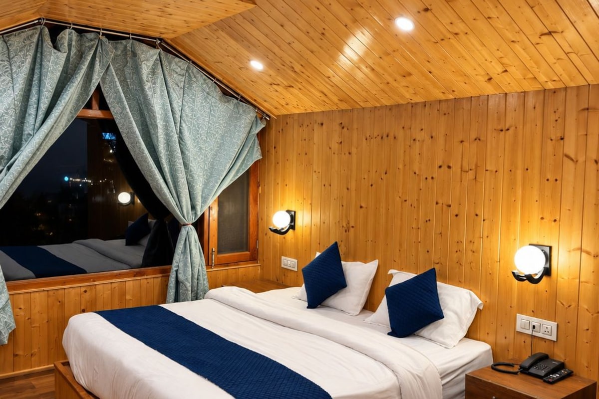 A wooden-paneled room with a large bed, two bedside tables, and a window with curtains.