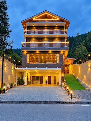 A multi-story hotel with a prominent entrance, balconies, and a well-lit facade. - Hotel Old Manali Retreat (Manali)