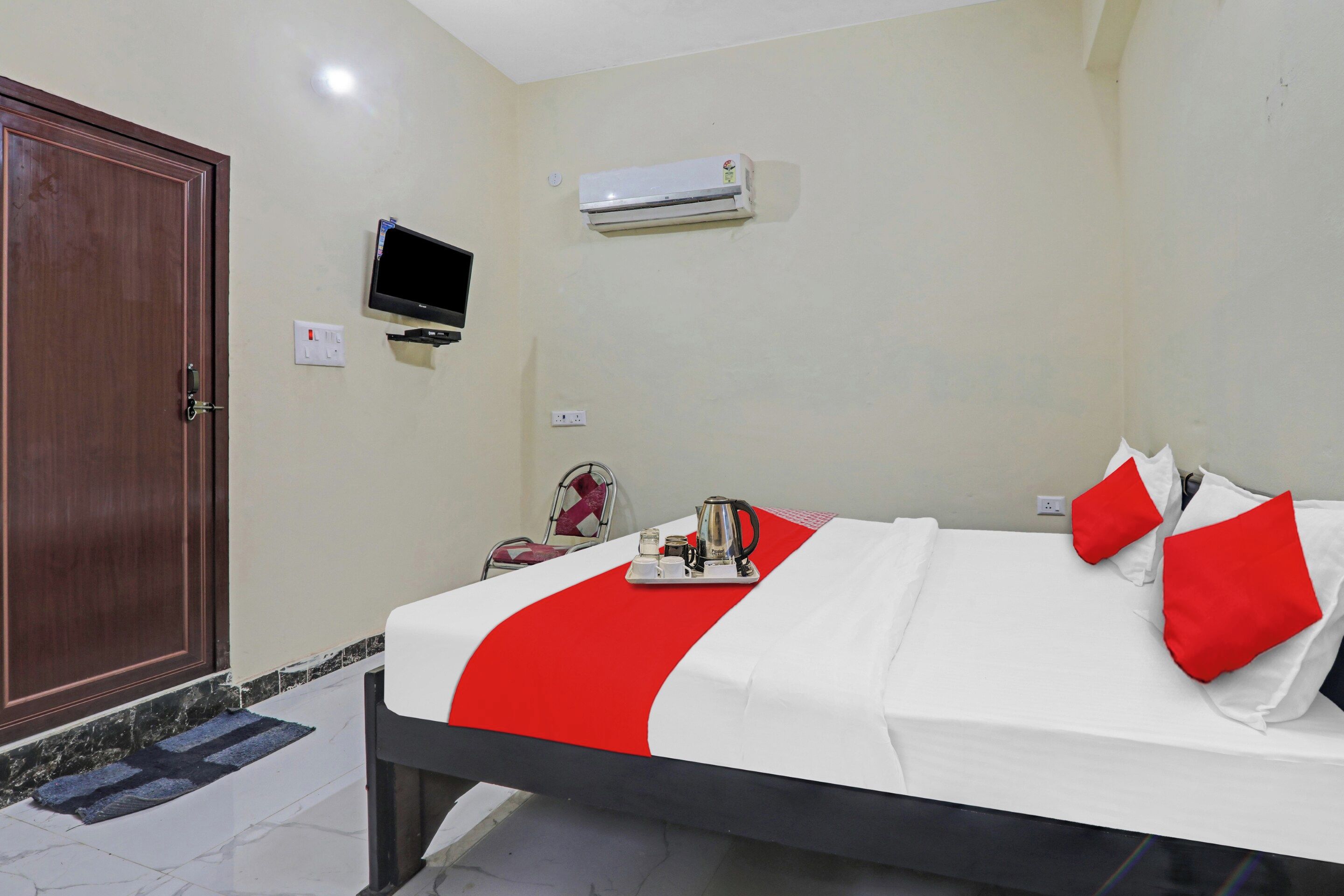Una habitación de hotel con cama, televisión, aire acondicionado y una puerta.