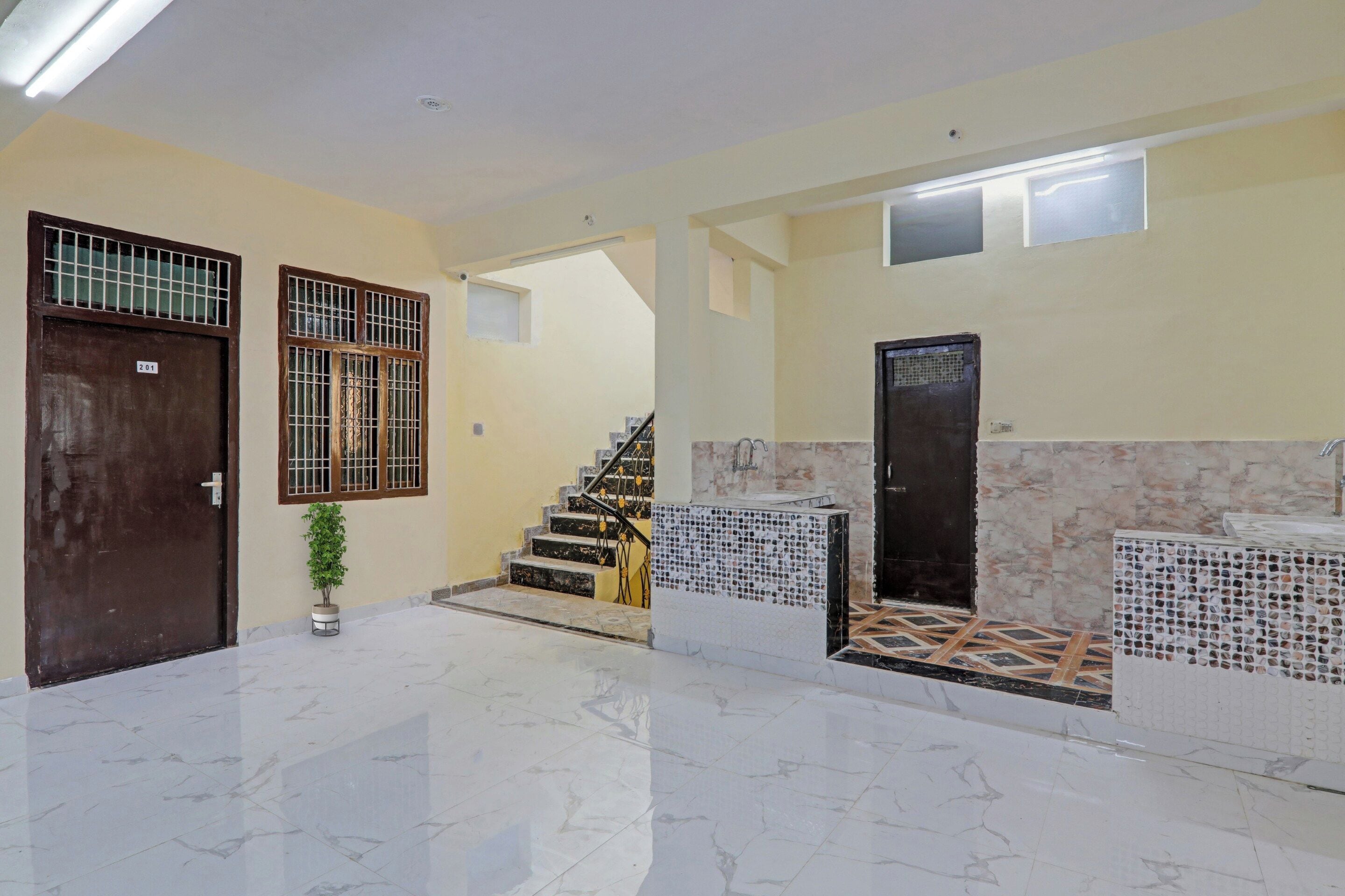 A clean, well-lit hallway with a marble floor, a staircase, and a door with a number sign.