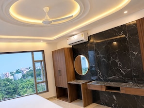 A modern bathroom with a vanity, a ceiling fan, and a large window offering a city view. - Hotel Benchmark Suites (indore)