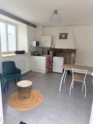 A compact living space with a kitchenette, a dining area with a table and chairs, a sofa, and a decorative light fixture. - New Listing (Condé-sur-Sarthe)