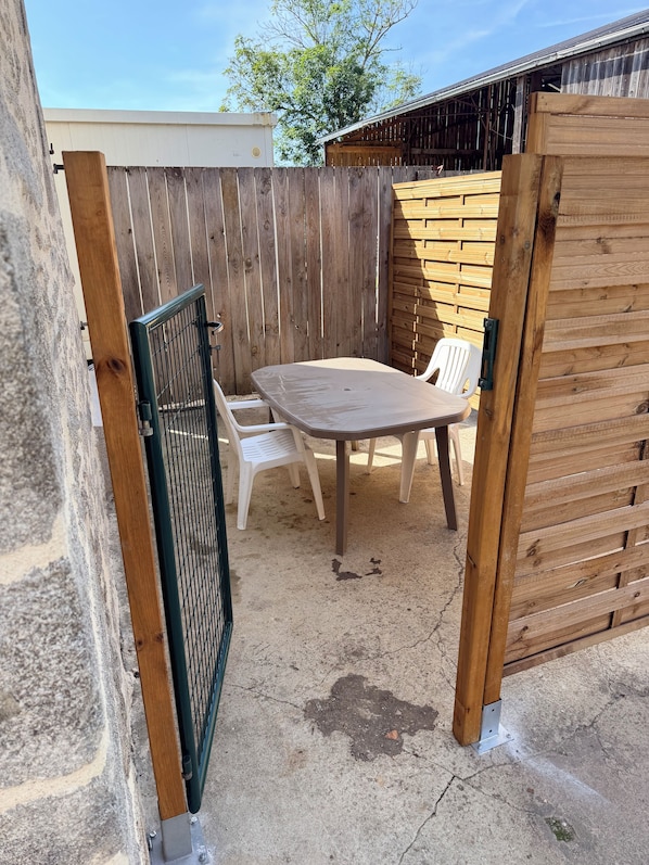A patio with a table and chairs, a wooden fence, and a gate.