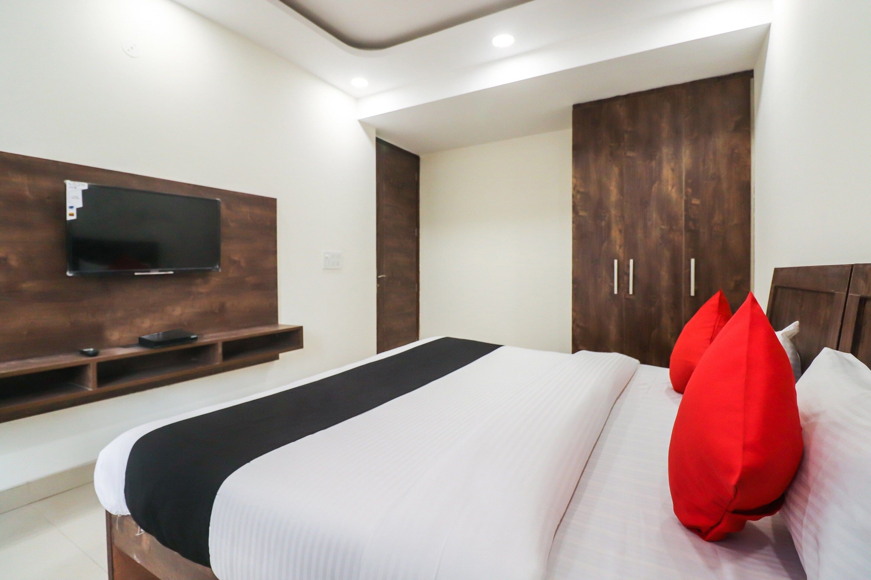 Ein modernes Hotelzimmer mit einem großen Bett, einem flachbildfernseher an der Wand und einem Kleiderschrank mit zwei Türen.