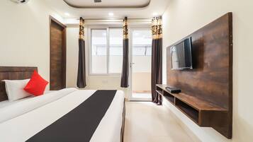 A hotel room with a bed, a TV mounted on the wall, and a window with curtains.