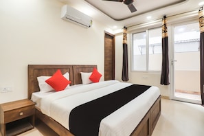A hotel room with a bed, nightstand, air conditioning unit, and a view of the outside. - Collection O by OYO Green Leaf Residency (Gurgaon)