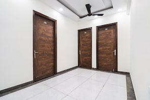 A hallway with three wooden doors, each marked with a number. - Collection O by OYO Green Leaf Residency (Gurgaon)