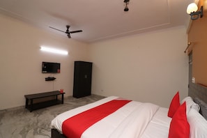 Un dormitorio con cama, televisor, armario, banca y ventilador de techo.