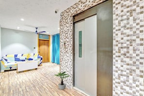 Una sala moderna con un sofá, una mesa de centro, una planta en maceta y una puerta con pantalla digital.