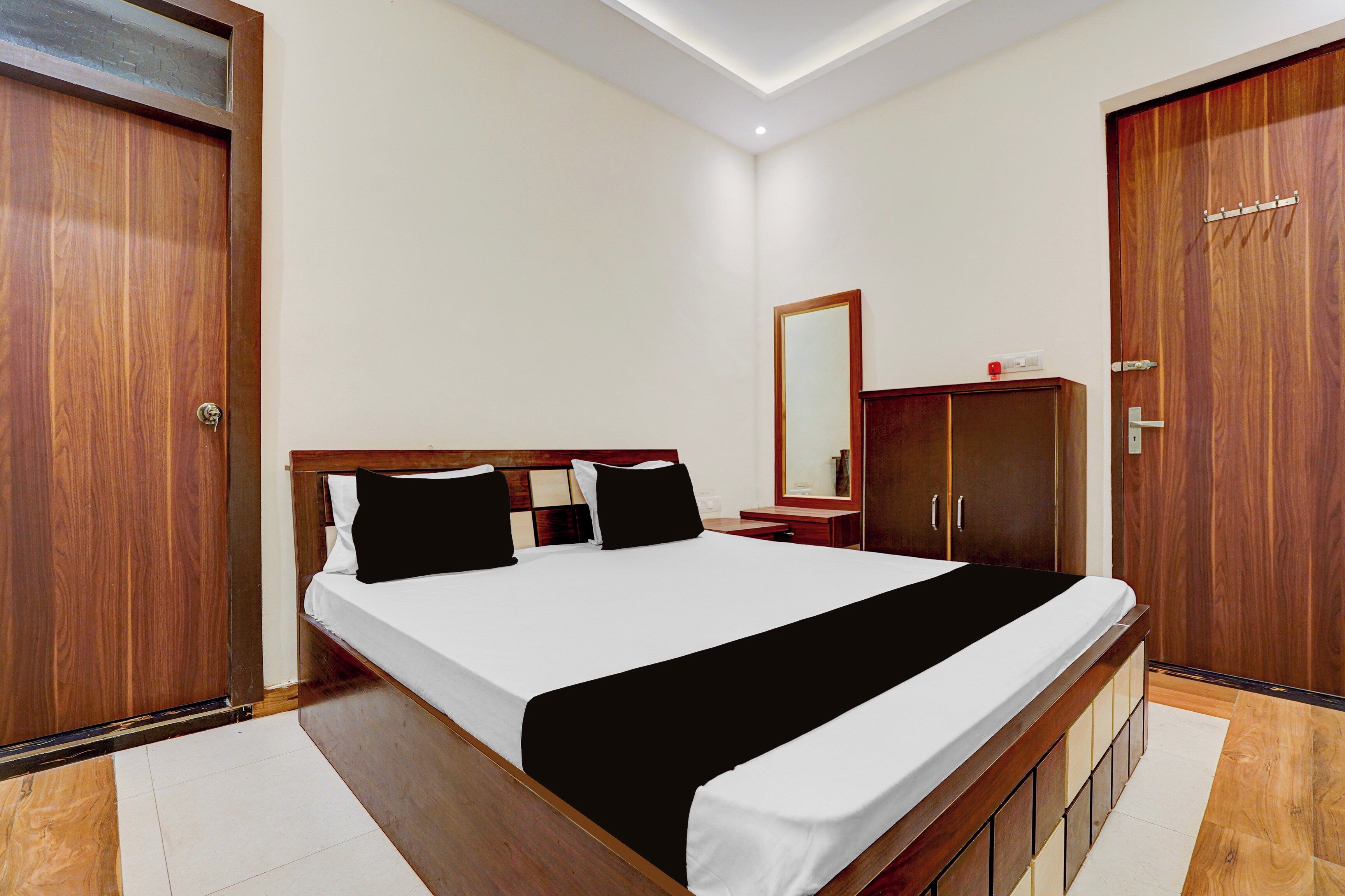 A hotel room with a bed, a wardrobe, a mirror, and a small table.