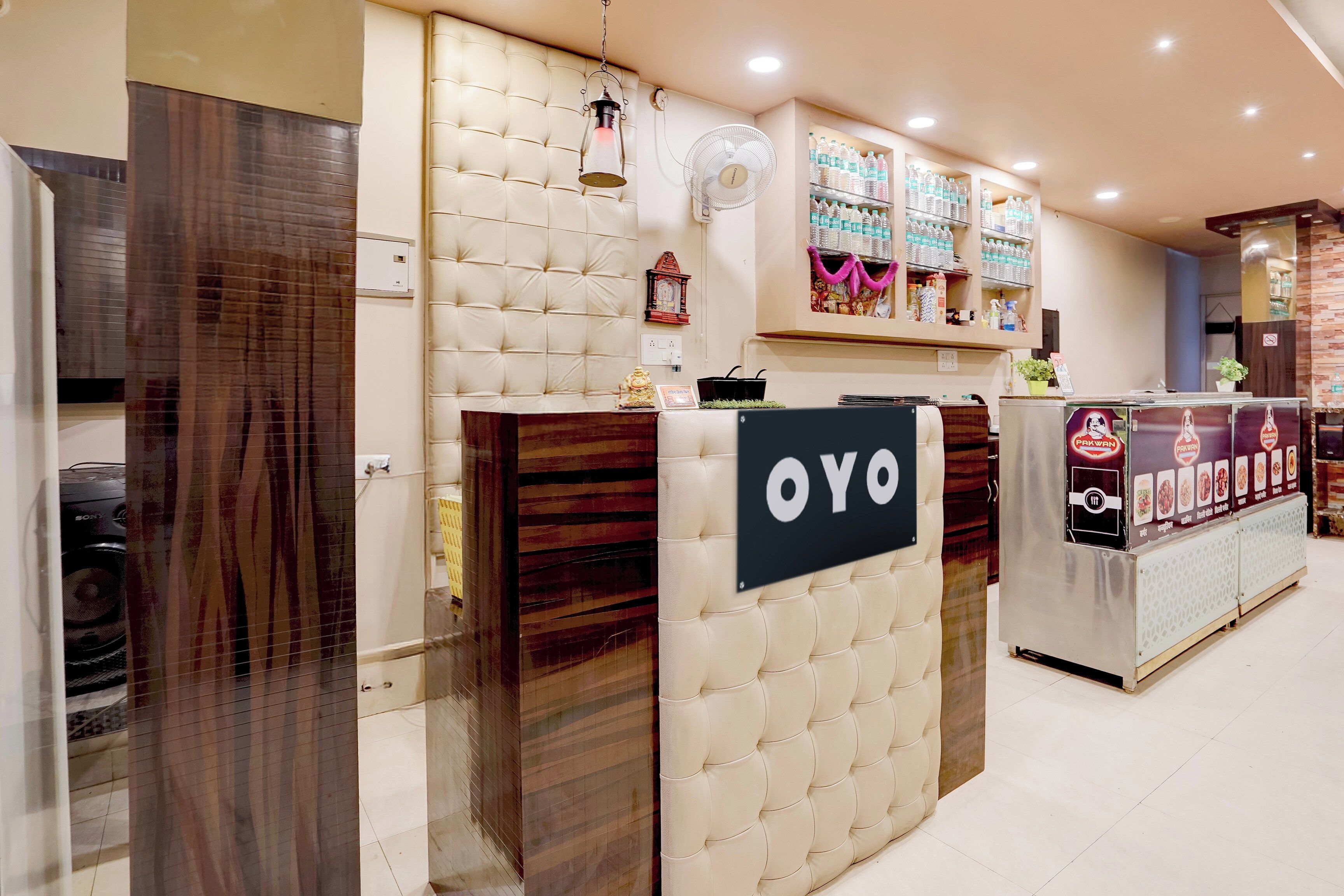 A reception area with a sign reading 'OYO' and a counter with bottled water and snacks.