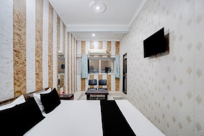 Een hotelkamer met een groot bed, een flatscreen televisie aan de muur, een klein tafeltje met stoelen en een raam met gordijnen.
