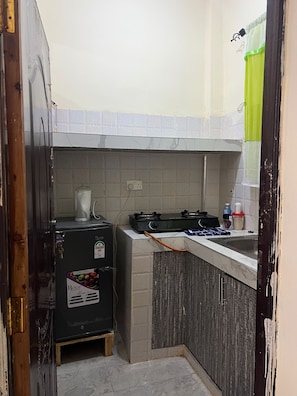 Une cuisine de taille réduite équipée d’un réfrigérateur, d’une cuisinière et d’un évier.
