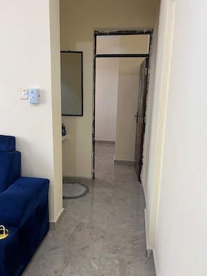 Un pasillo con una silla azul, un marco de puerta y piso de baldosas.