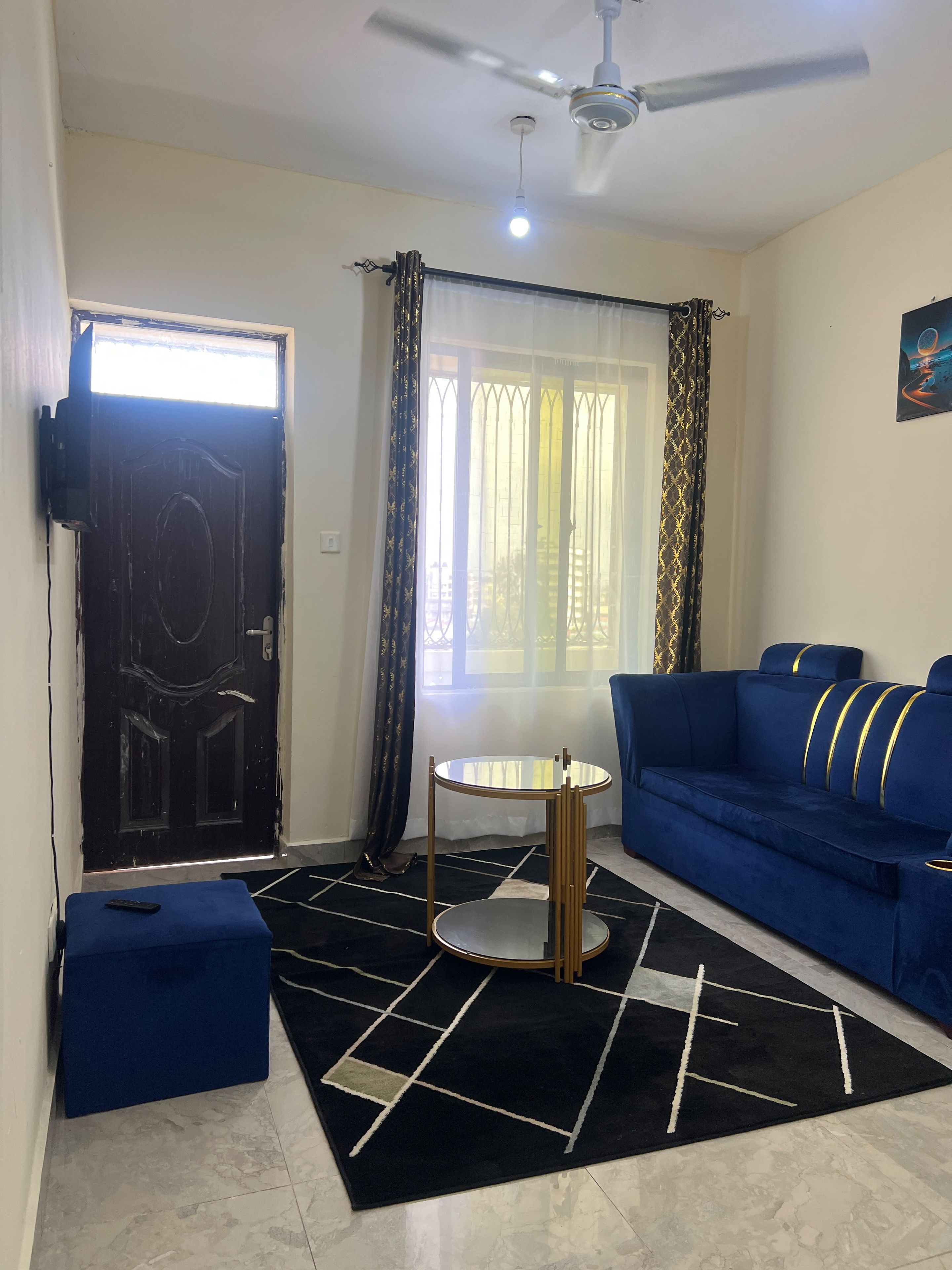 Una sala de estar con un sofá, una mesita redonda y un ventilador de techo.