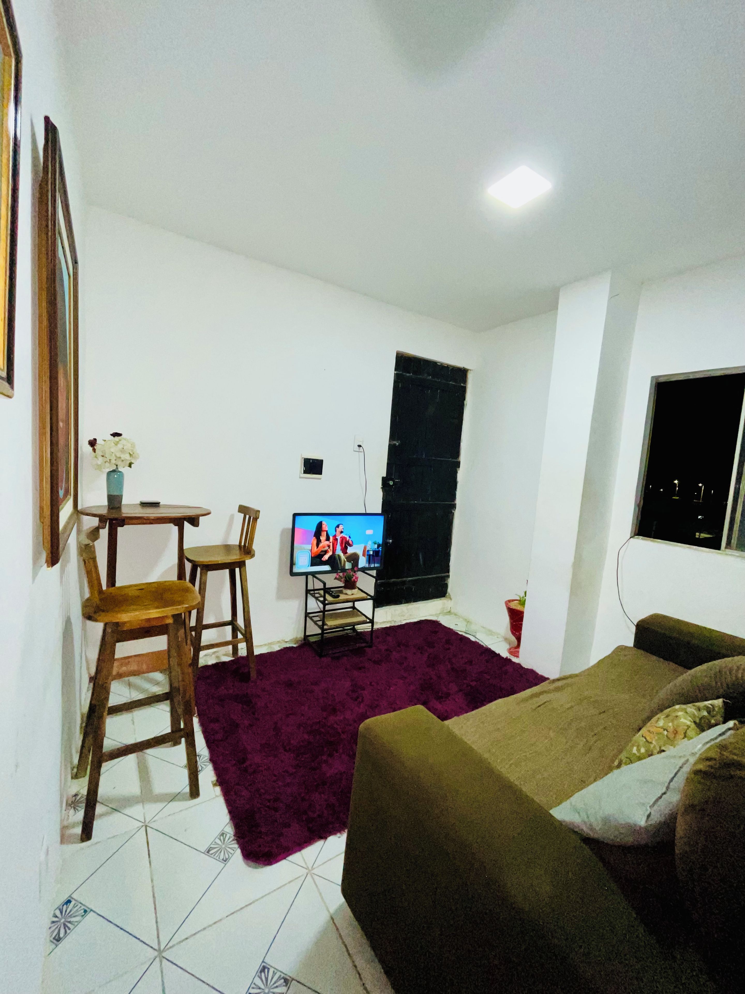 Habitació amb llit, televisió, taula petita amb cadires i finestra.