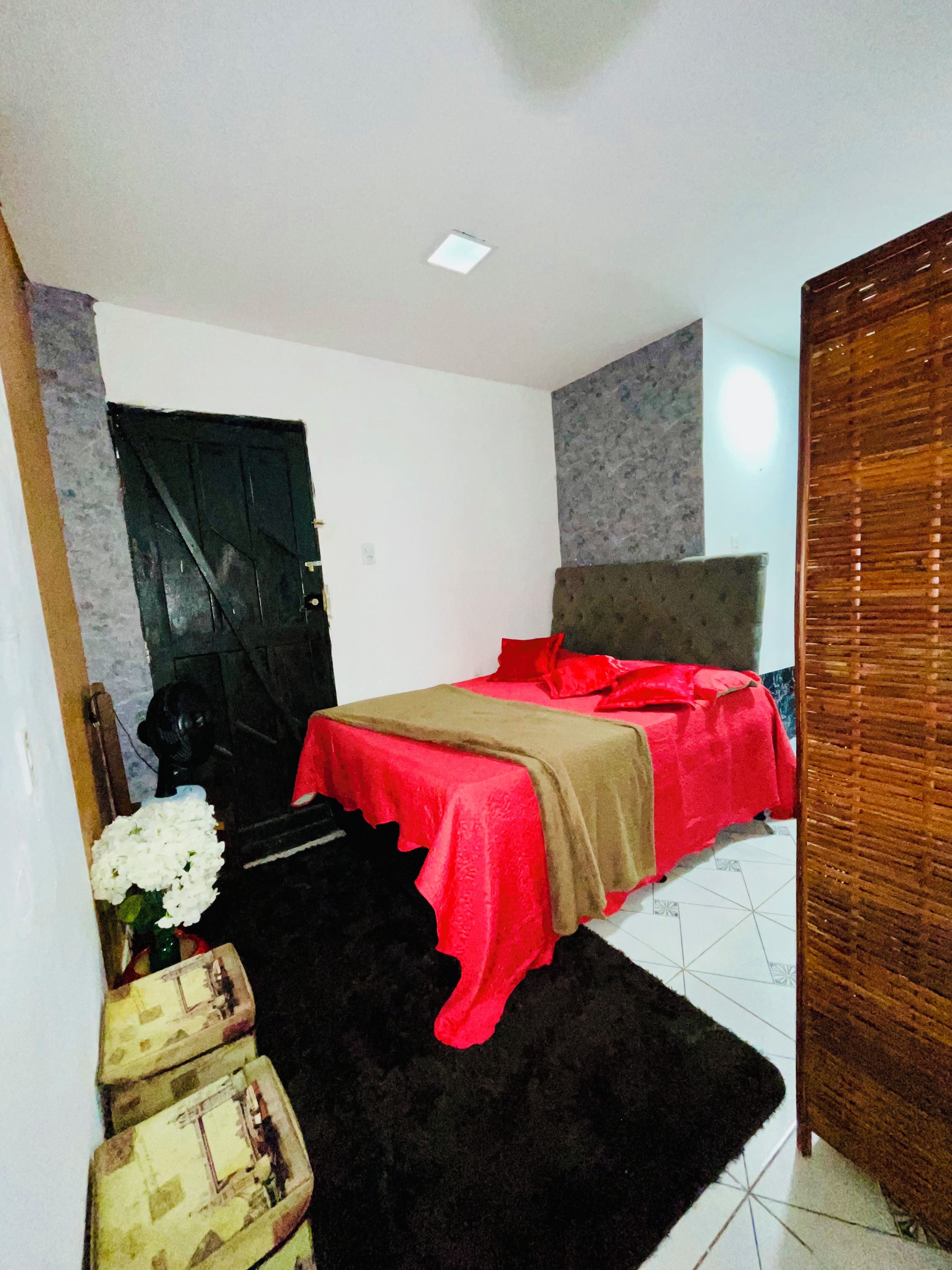 Een slaapkamer met een bed, een zwart tapijt, een houten garderobe en een witte deur.
