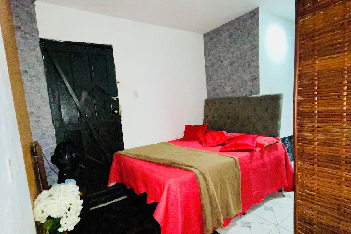Een slaapkamer met een bed, een zwart vloerkleed, een houten garderobe en een deur.